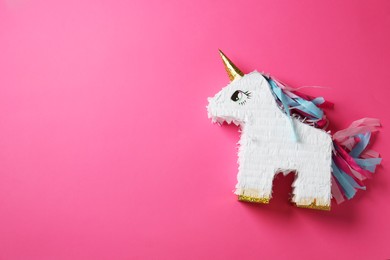 Photo of Bright pinata in shape of unicorn on pink background, top view. Space for text