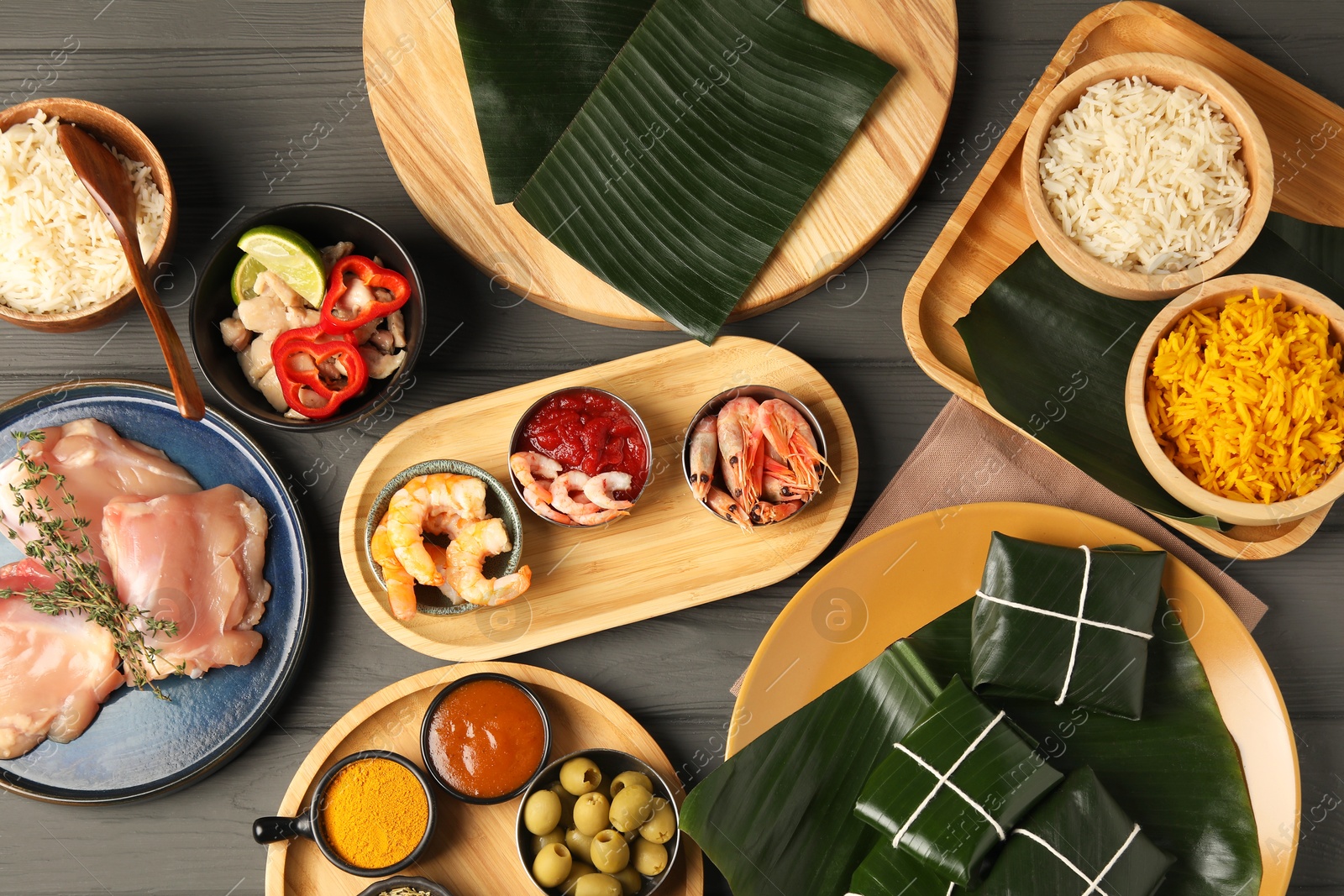 Photo of Different food wrapped in banana leaves, products, sauce and spices on wooden table, flat lay