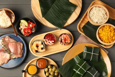 Different food wrapped in banana leaves, products, sauce and spices on wooden table, flat lay