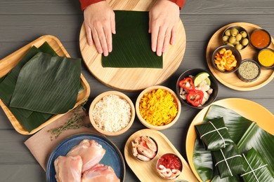 Photo of Woman with banana leaf at wooden table with different products, sauce and spices, top view. Healthy eco serving