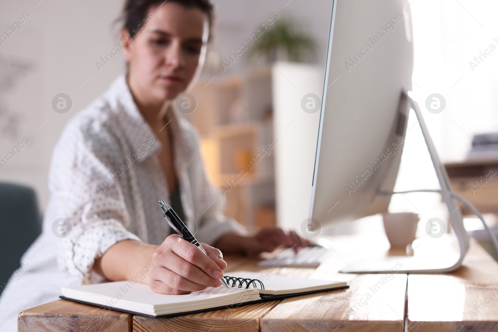 Photo of Woman working at wooden desk indoors, selective focus. Home office