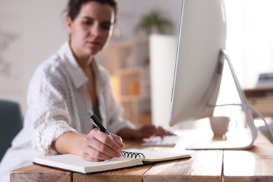 Photo of Woman working at wooden desk indoors, selective focus. Home office