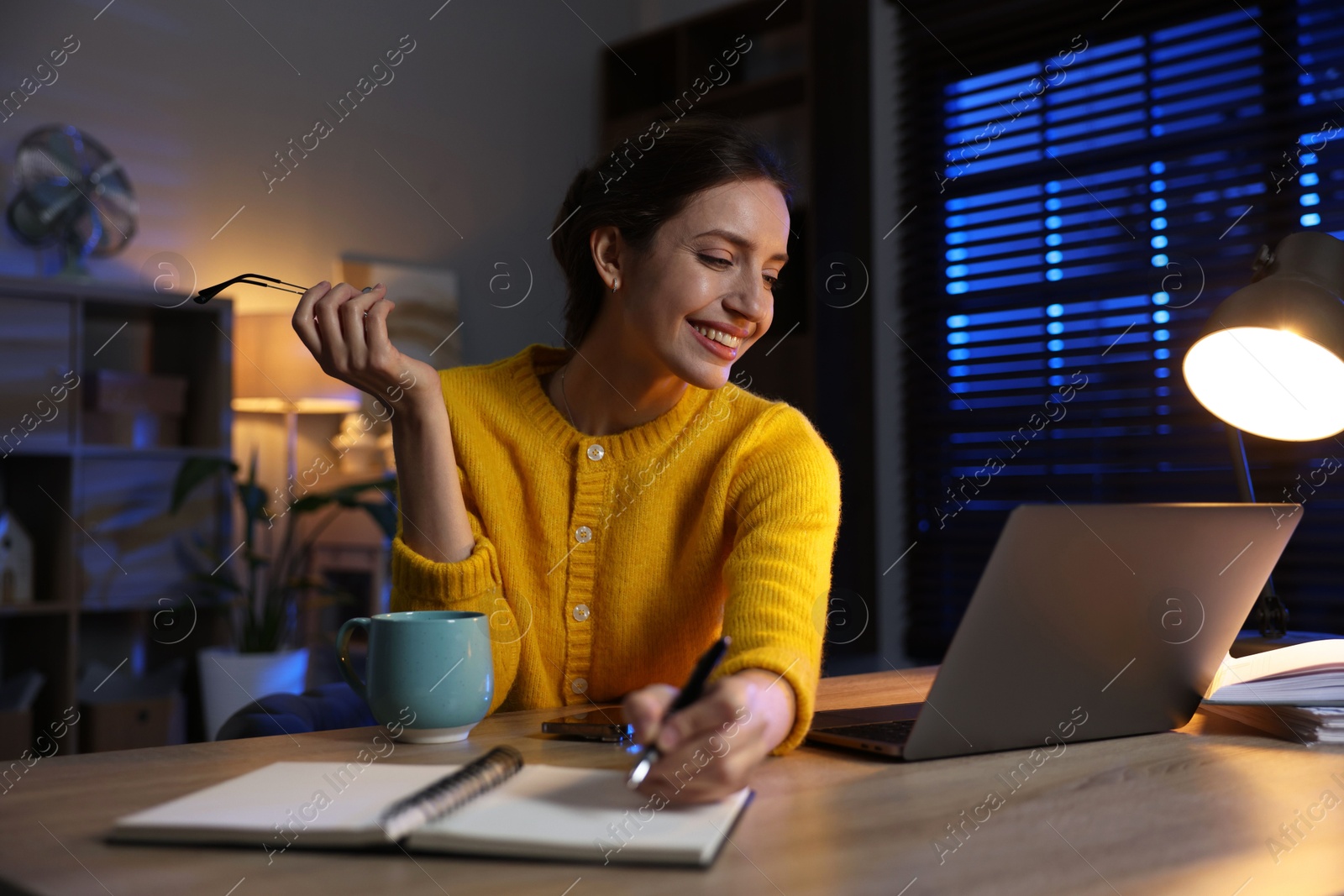 Photo of Woman taking notes while working at desk in home office