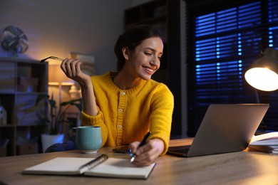 Photo of Woman taking notes while working at desk in home office