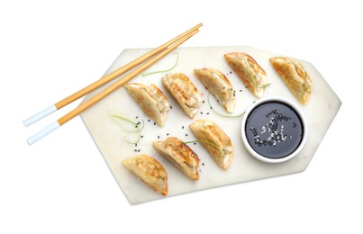 Photo of Delicious fried gyoza dumplings with sesame seeds, microgreens and soy sauce isolated on white, top view