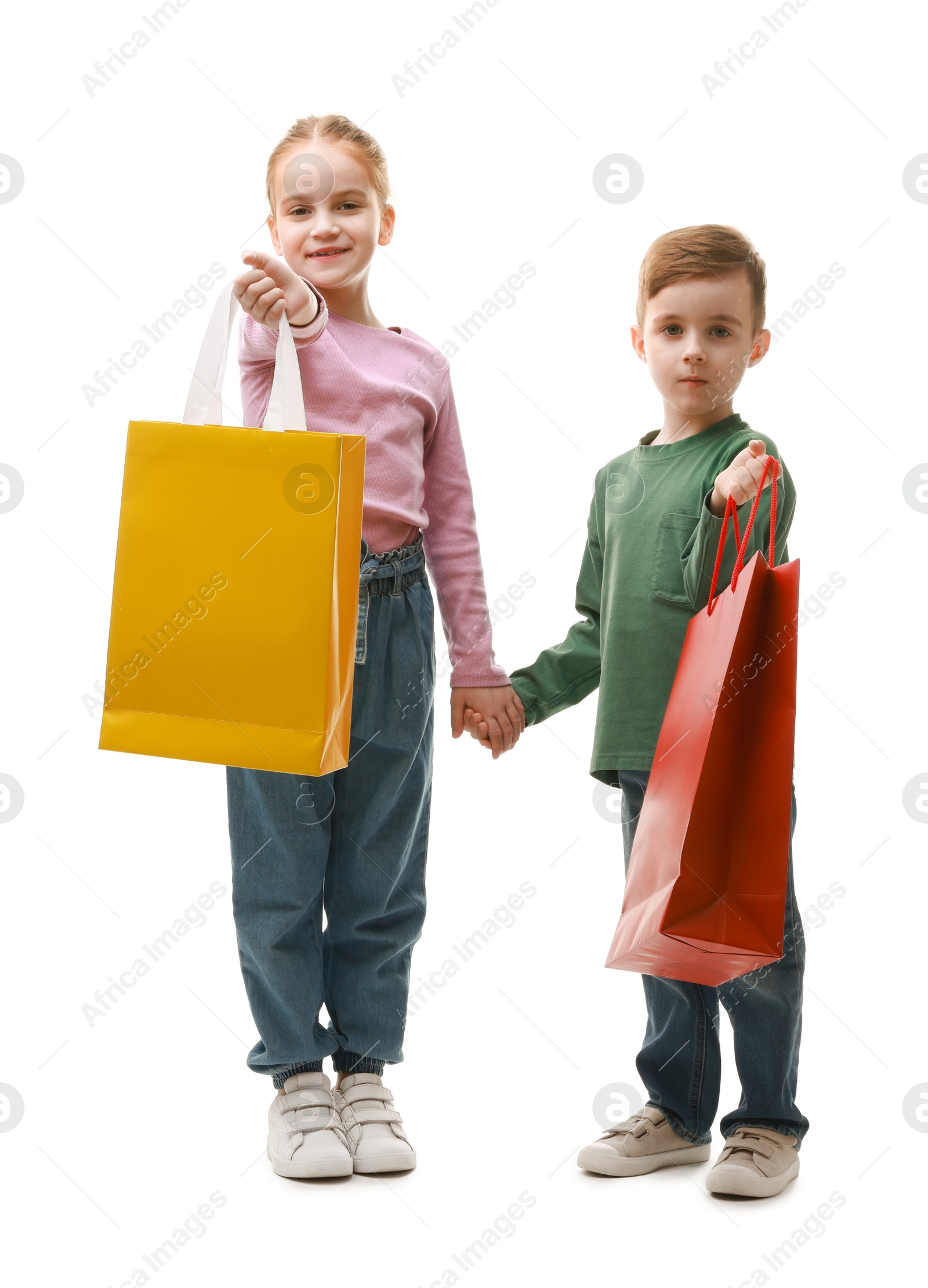 Photo of Cute little friends with shopping bags holding hands on white background