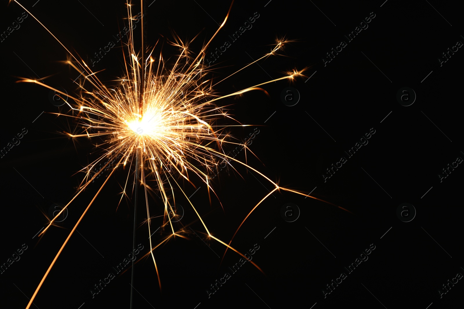 Photo of Bright burning sparkler on black background, closeup. Space for text