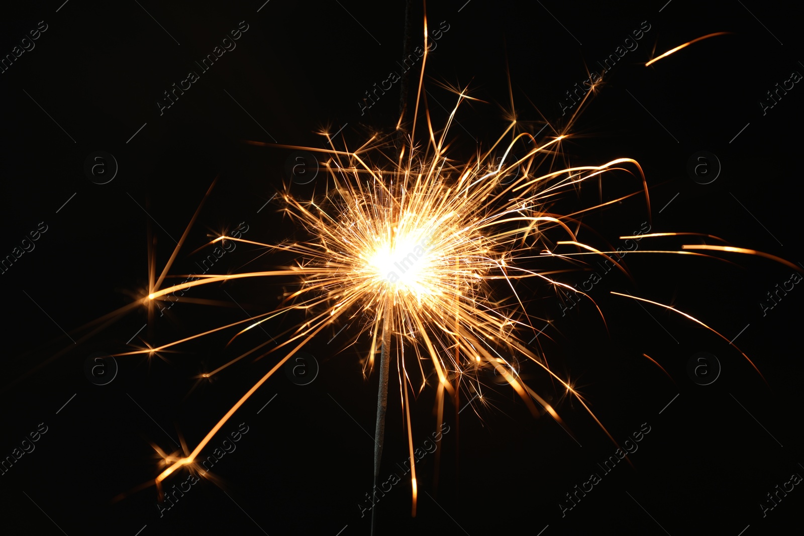 Photo of Bright burning sparkler on black background, closeup