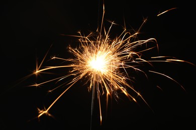 Photo of Bright burning sparkler on black background, closeup