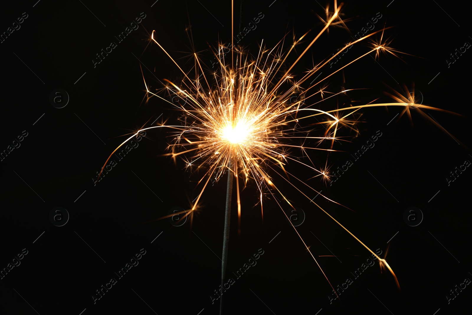 Photo of Bright burning sparkler on black background, closeup