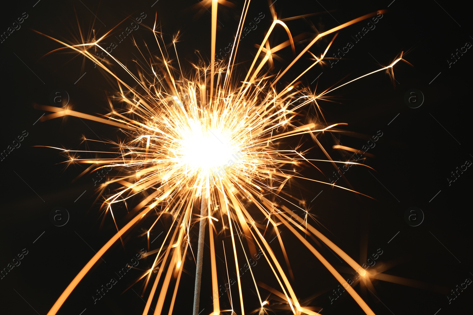 Photo of Bright burning sparkler on black background, closeup