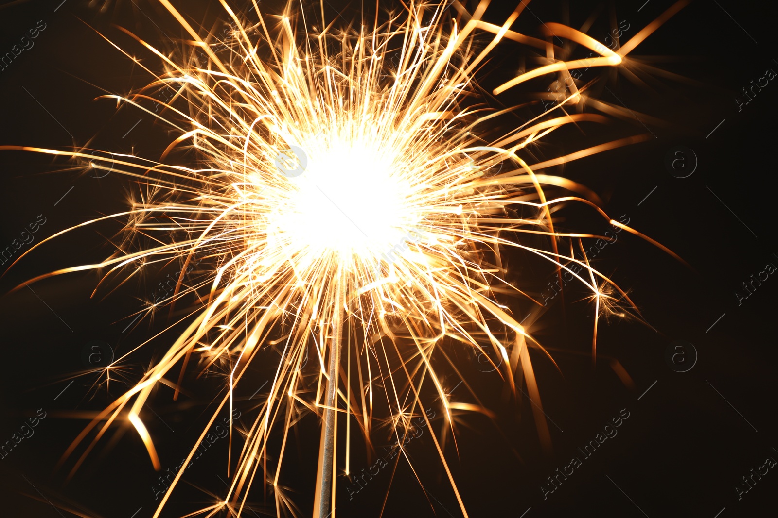 Photo of Bright burning sparkler on black background, closeup