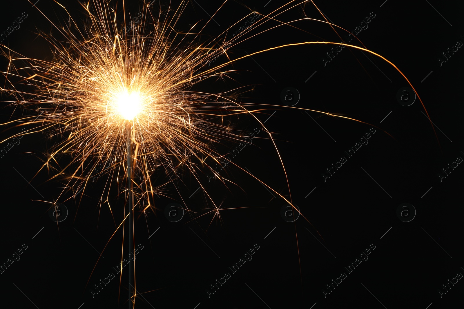 Photo of Bright burning sparkler on black background, closeup