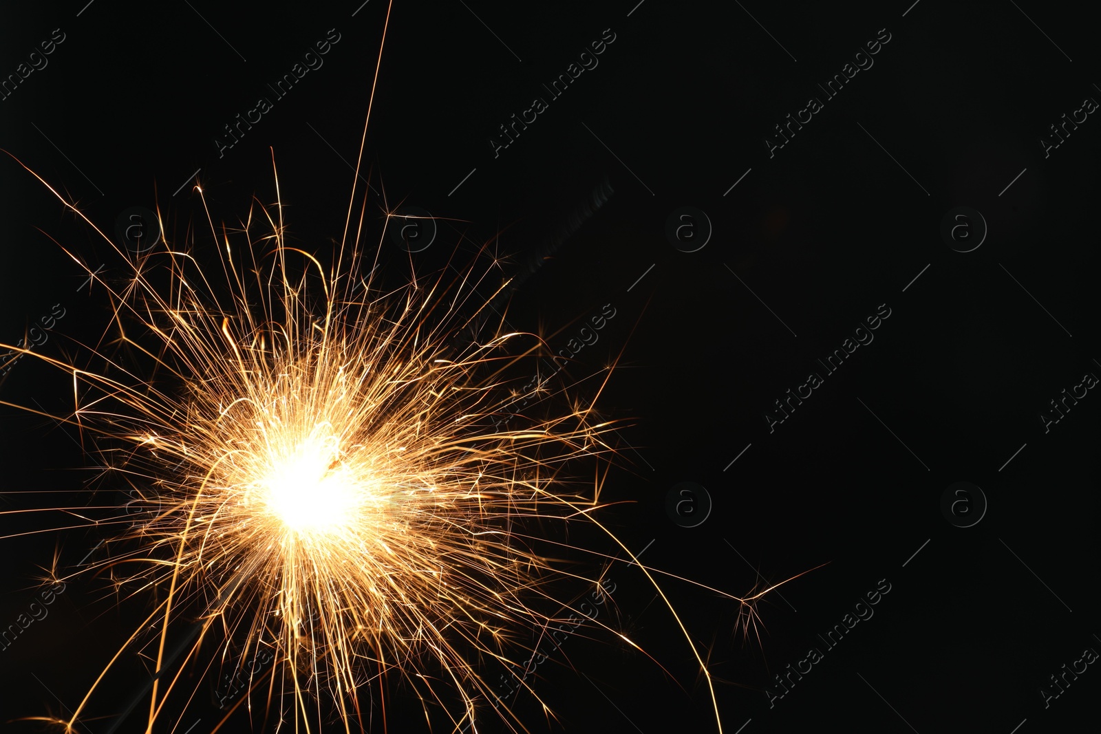 Photo of Bright burning sparkler on black background, closeup. Space for text