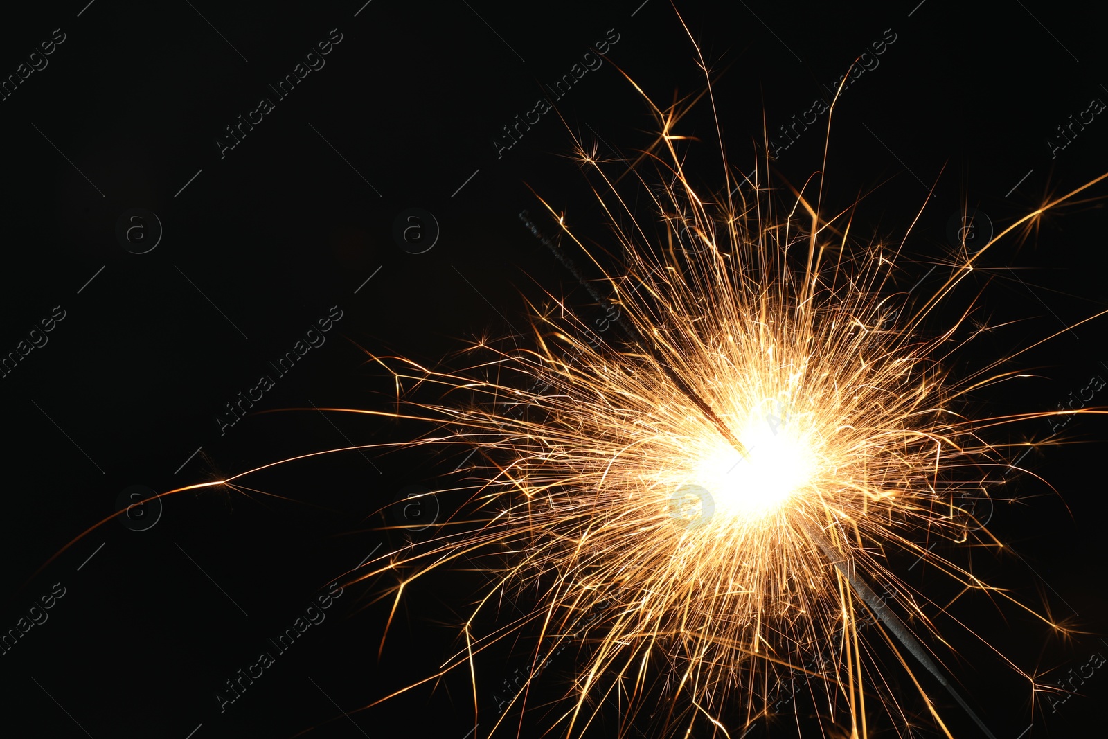 Photo of Bright burning sparkler on black background, closeup. Space for text