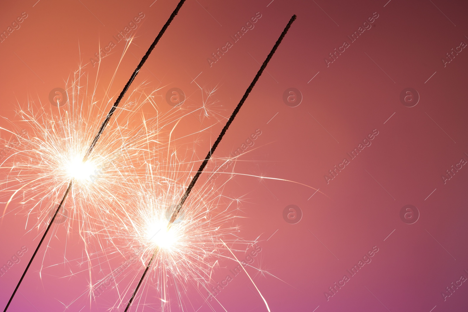 Photo of Bright burning sparklers on color background, closeup. Space for text