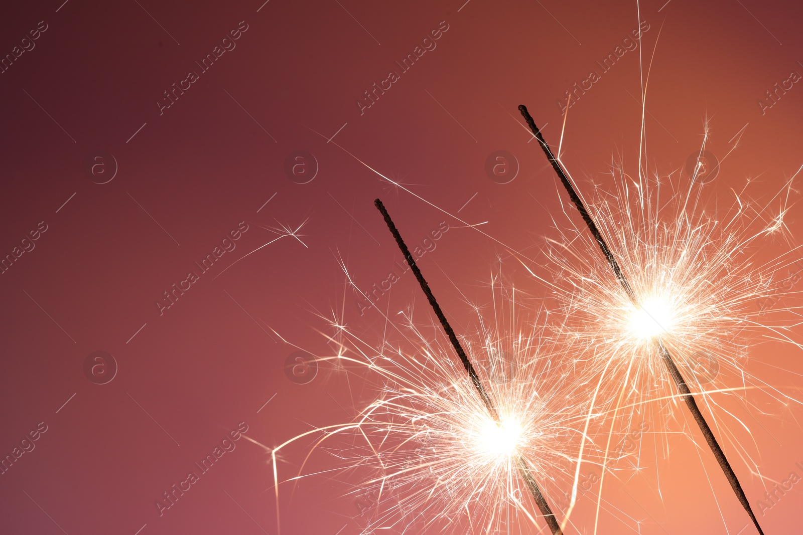 Photo of Bright burning sparklers on color background, closeup. Space for text