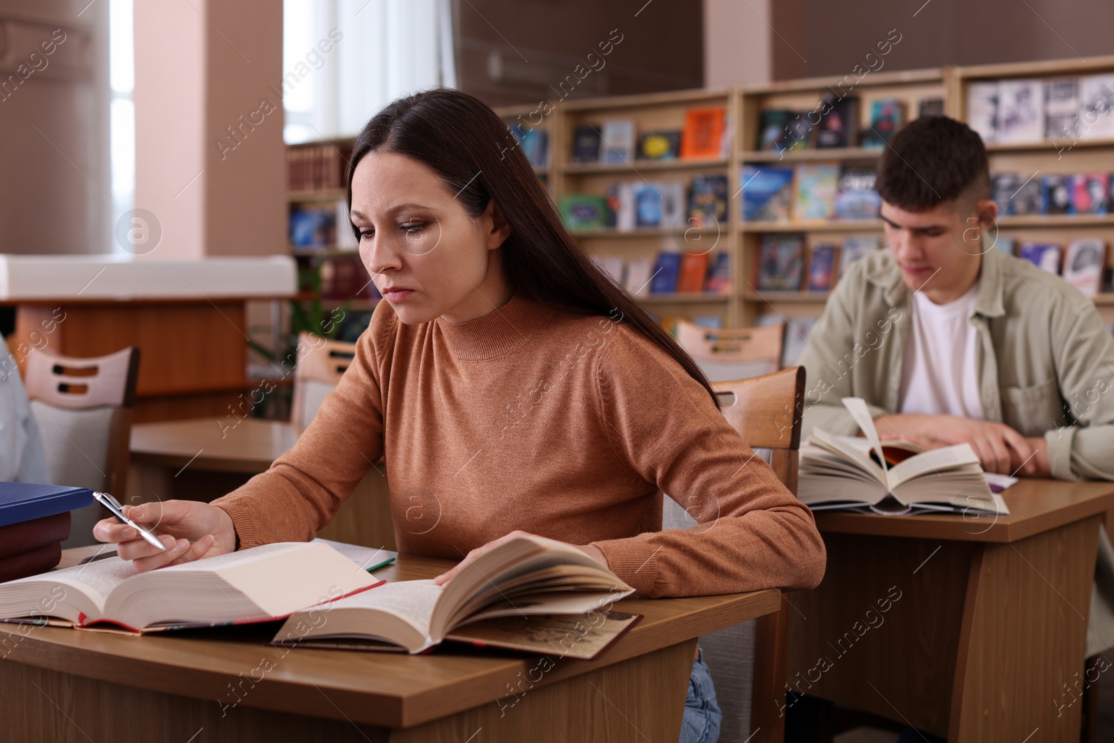 Photo of Beautiful woman with books at desk in public library