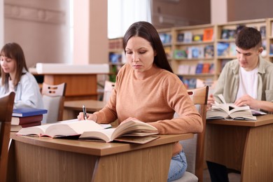 Photo of Beautiful woman with books at desk in public library