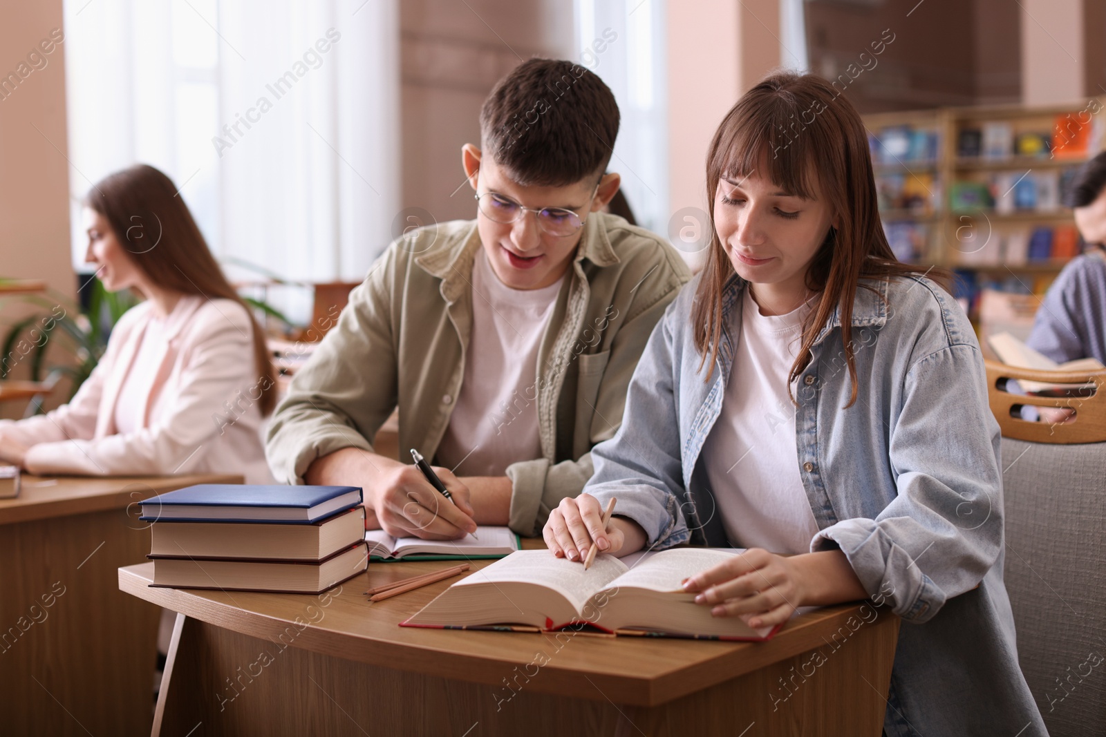 Photo of People reading different books at desks in public library