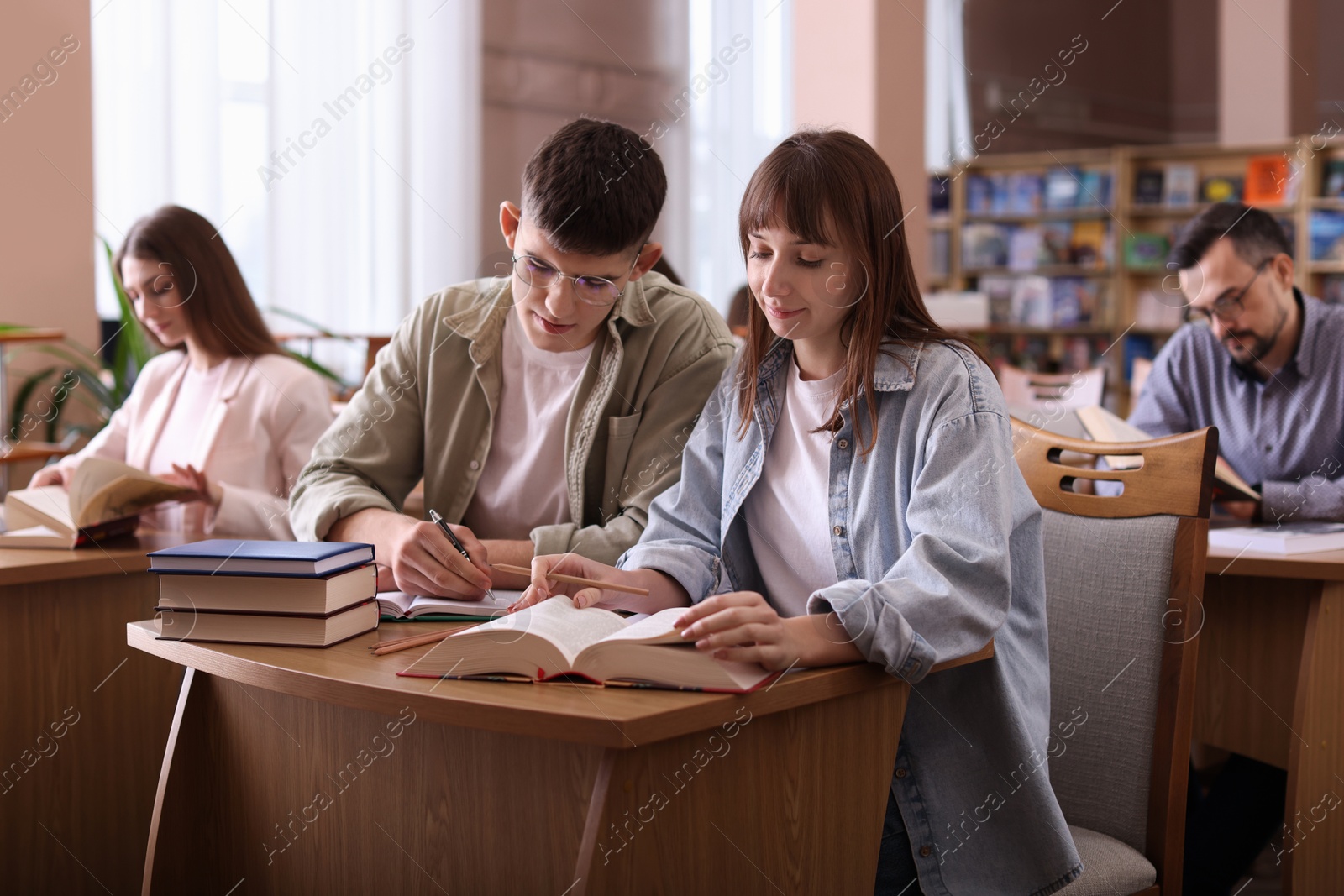 Photo of People reading different books at desks in public library