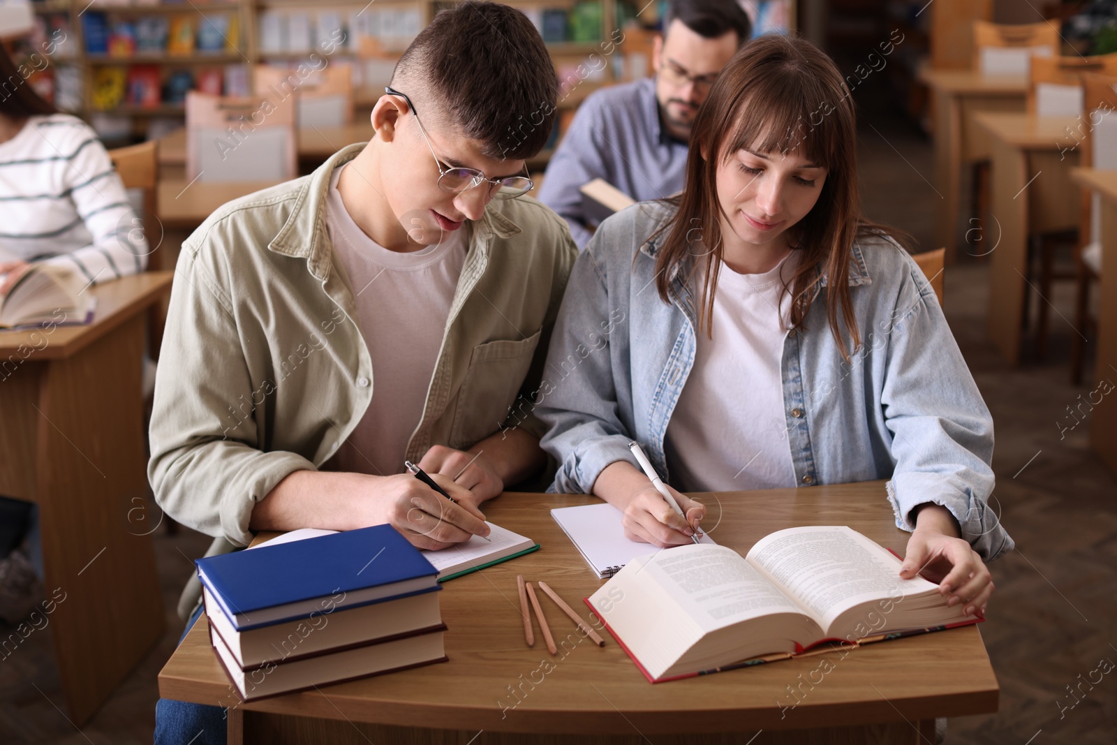 Photo of People reading different books at desks in public library