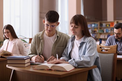 People reading different books at desks in public library