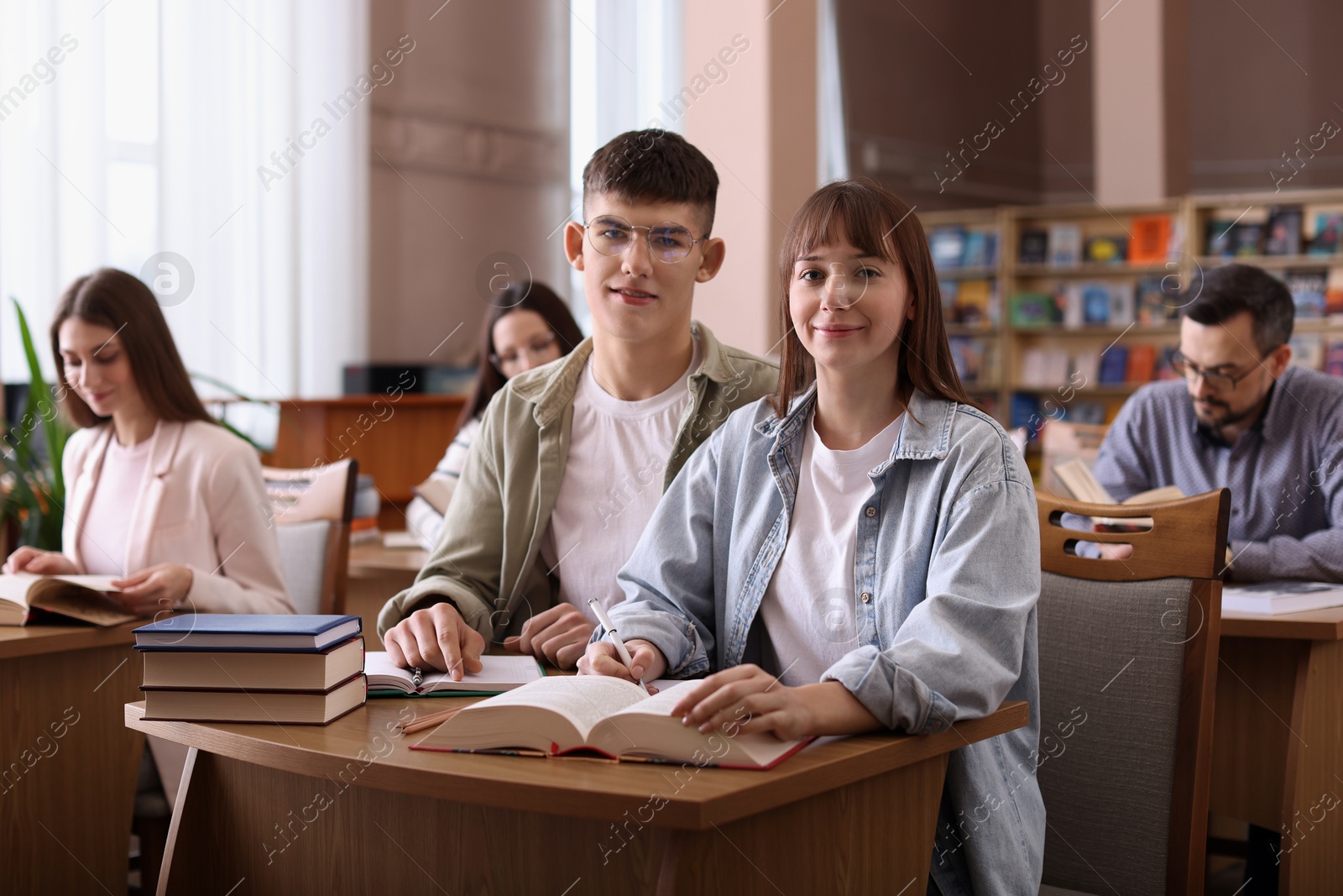 Photo of Portrait of young couple with books at desk in public library