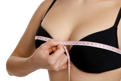 Photo of Woman in beautiful bra measuring breast circumference on white background, closeup