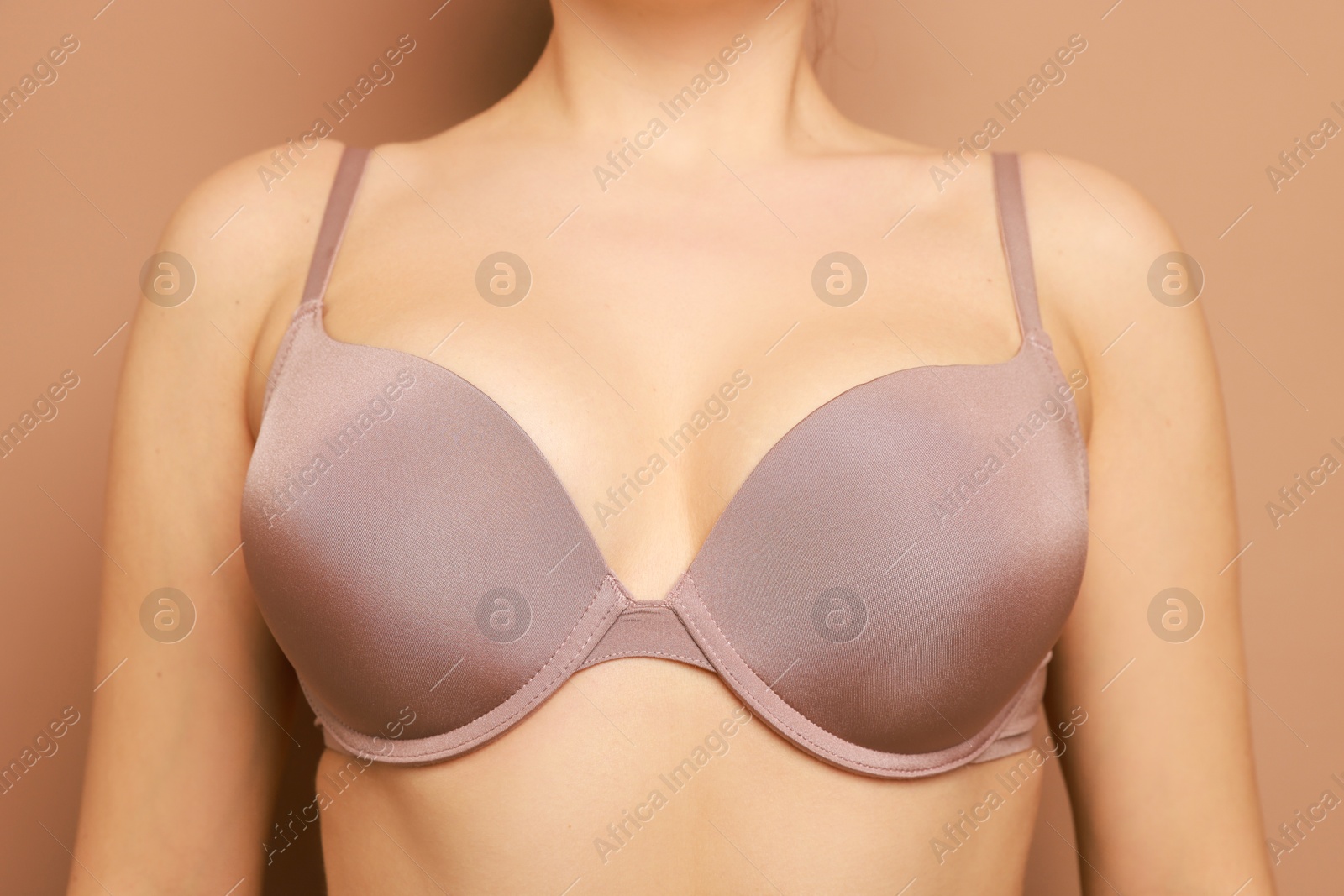 Photo of Woman wearing beautiful bra on beige background, closeup