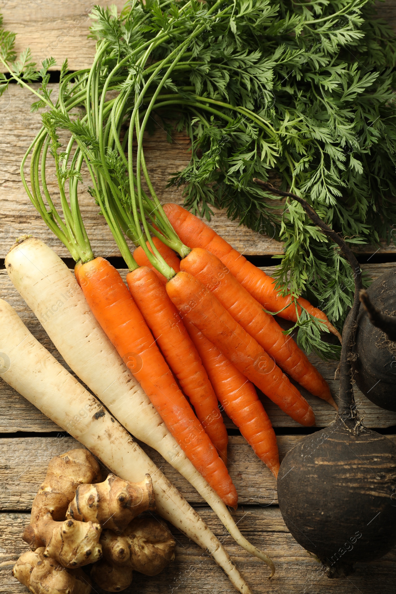 Photo of Different root vegetables on wooden table, flat lay