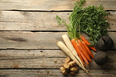 Photo of Different root vegetables on wooden table, flat lay. Space for text