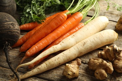 Photo of Different root vegetables on wooden table, closeup