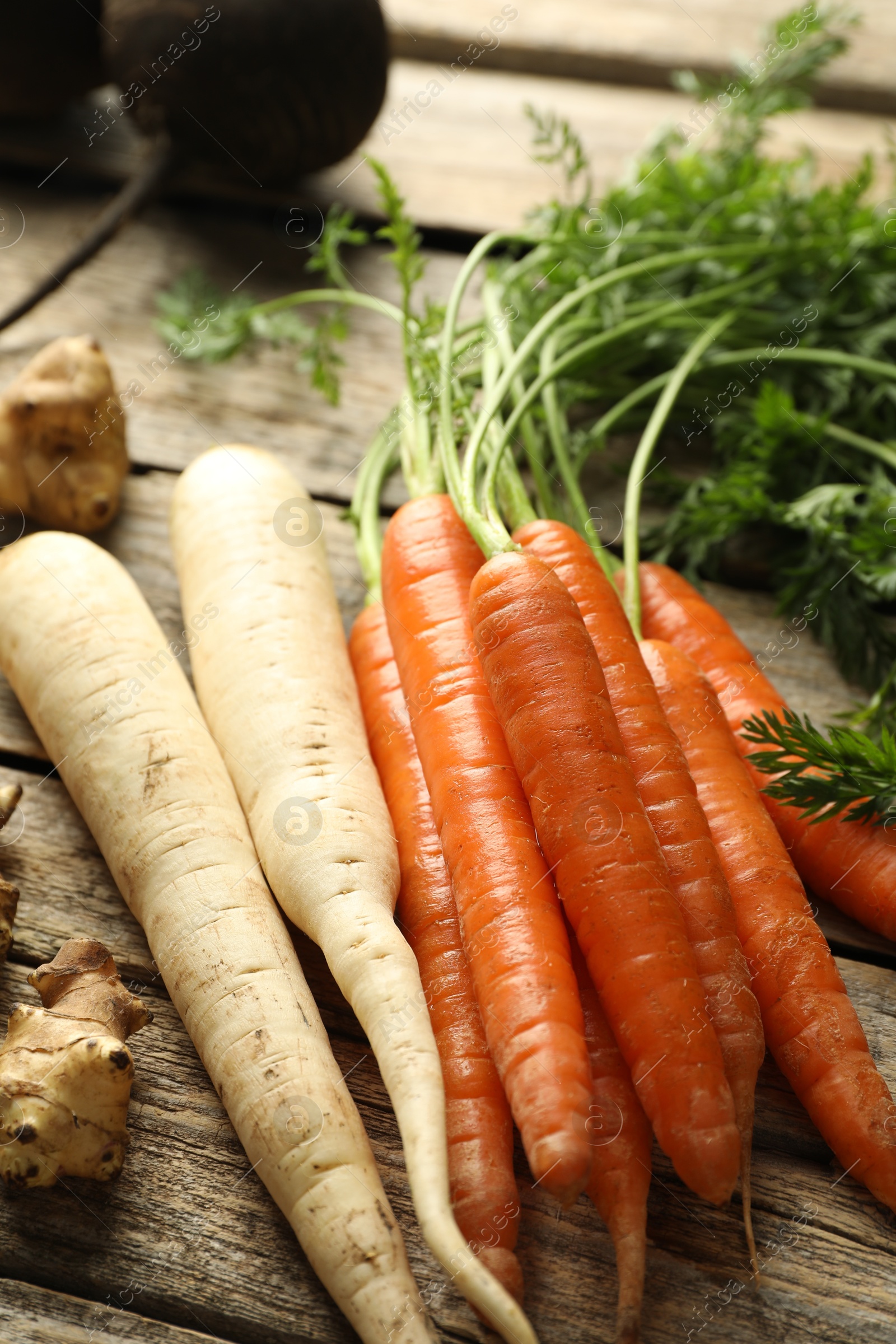 Photo of Different root vegetables on wooden table, closeup