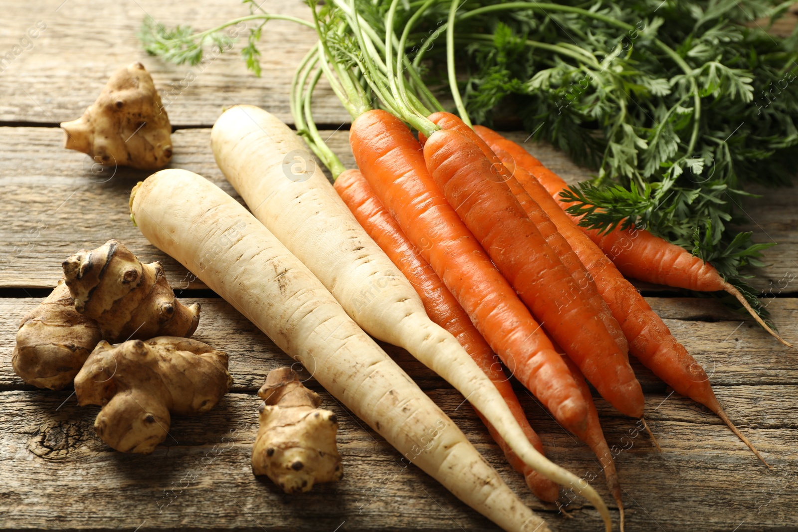 Photo of Different root vegetables on wooden table, closeup