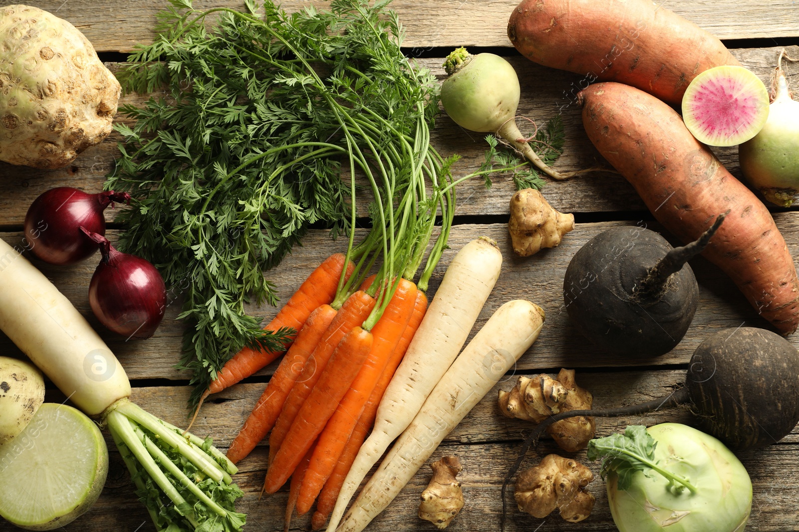 Photo of Different root vegetables on wooden table, flat lay