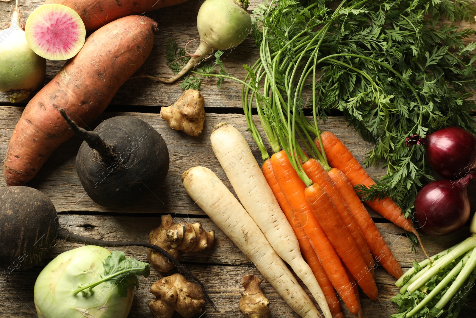 Photo of Different root vegetables on wooden table, flat lay