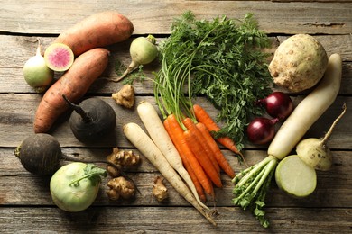 Photo of Different root vegetables on wooden table, flat lay