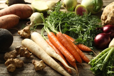 Photo of Different root vegetables on wooden table, closeup