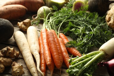 Photo of Different root vegetables on wooden table, closeup