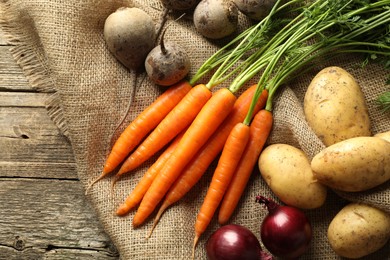 Photo of Different root vegetables on wooden table, flat lay