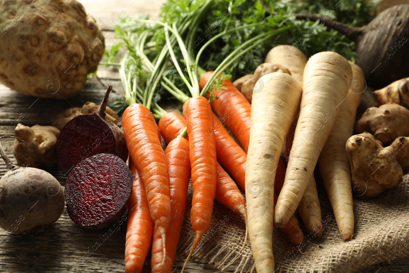 Photo of Different root vegetables on wooden table, closeup