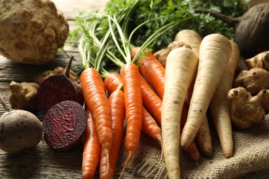 Photo of Different root vegetables on wooden table, closeup