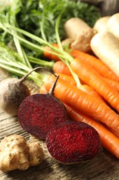 Photo of Different root vegetables on wooden table, closeup