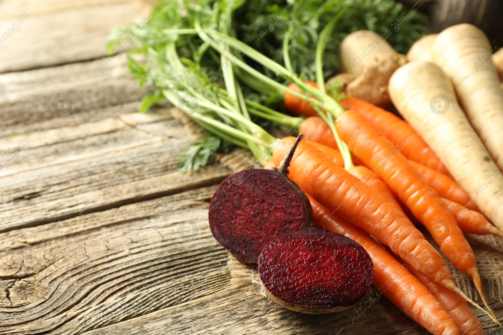 Photo of Different root vegetables on wooden table, closeup