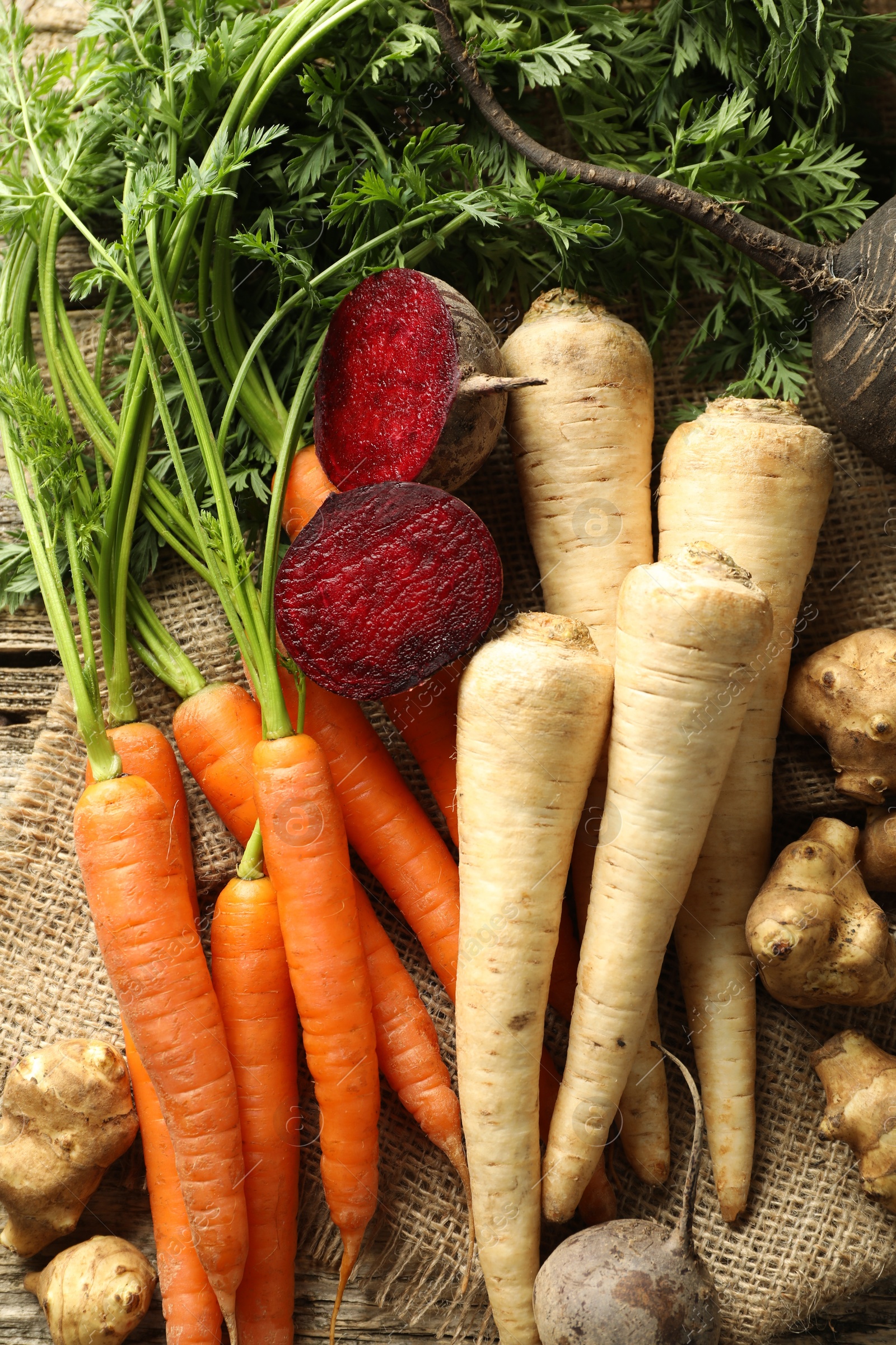 Photo of Different root vegetables on wooden table, flat lay