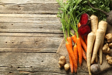 Photo of Different root vegetables on wooden table, flat lay. Space for text