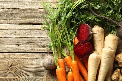 Photo of Different root vegetables on wooden table, flat lay. Space for text