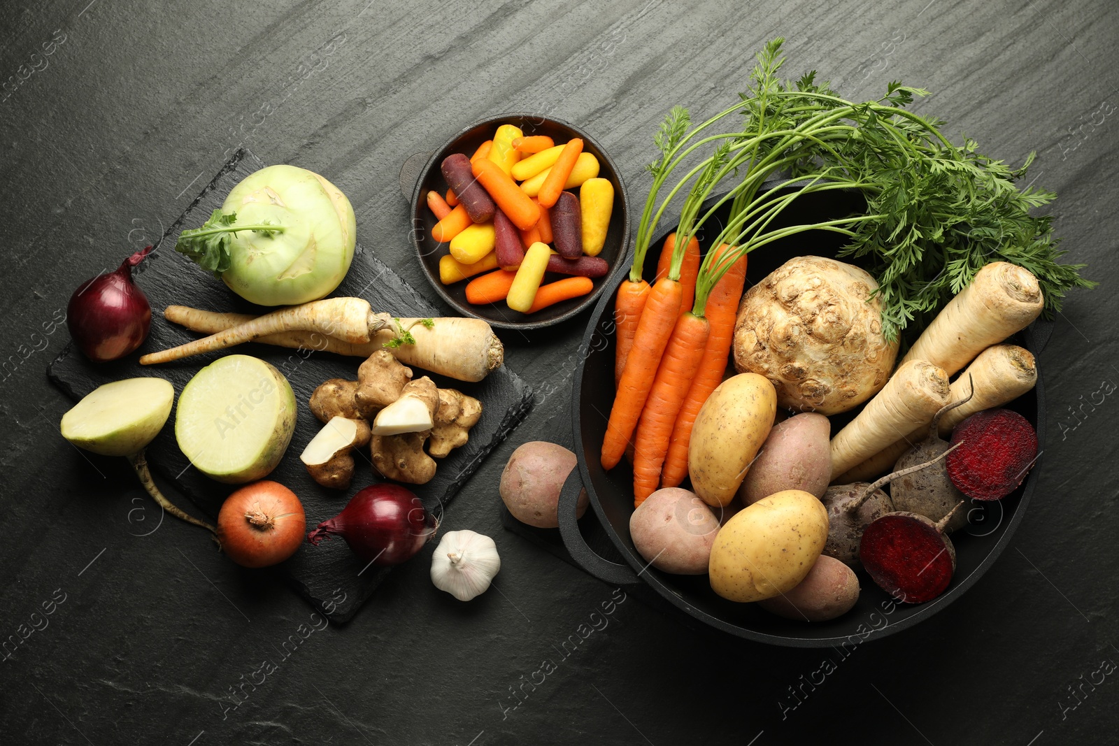 Photo of Different raw root vegetables on black table, flat lay