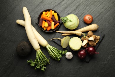 Photo of Different raw root vegetables on black table, flat lay